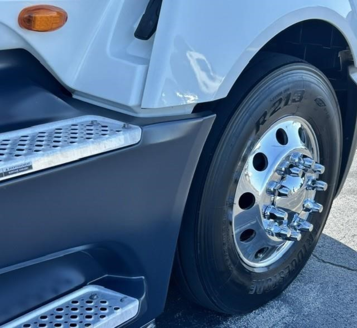 Truck front wheel and step showing chrome hubcap, treaded tire with 'R213' marking, and metal step; part of International LT conventional sleeper