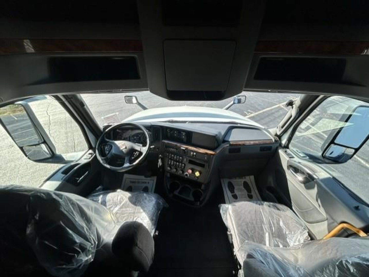 Interior of a 2021 International LT sleeper cab showing steering wheel, dashboard, center console, and plastic-covered seats.