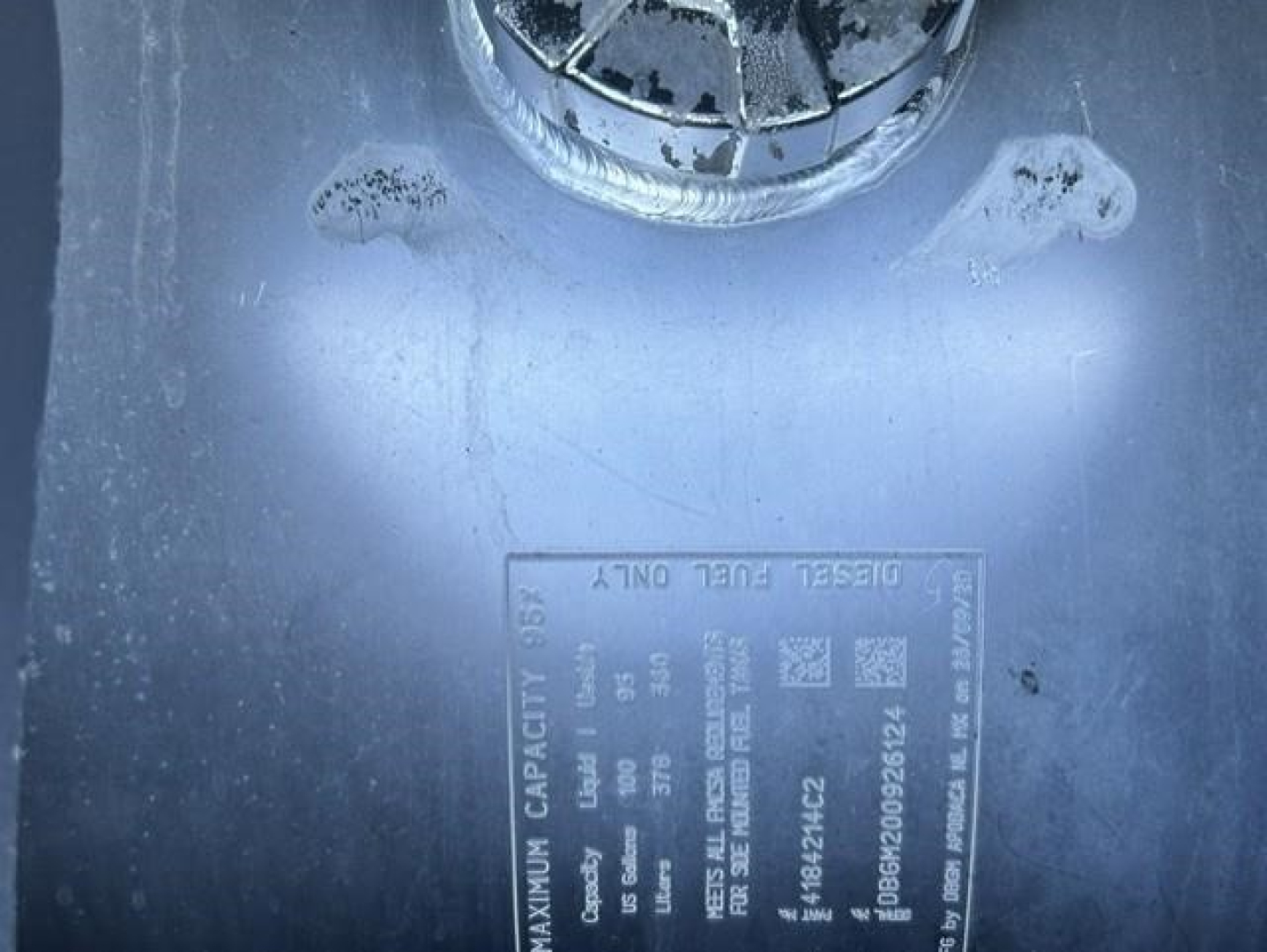Label on truck showing maximum capacity and tire load data with a circular cap above. Text includes details like 'MAXIMUM CAPACITY' and various numeric specifications.