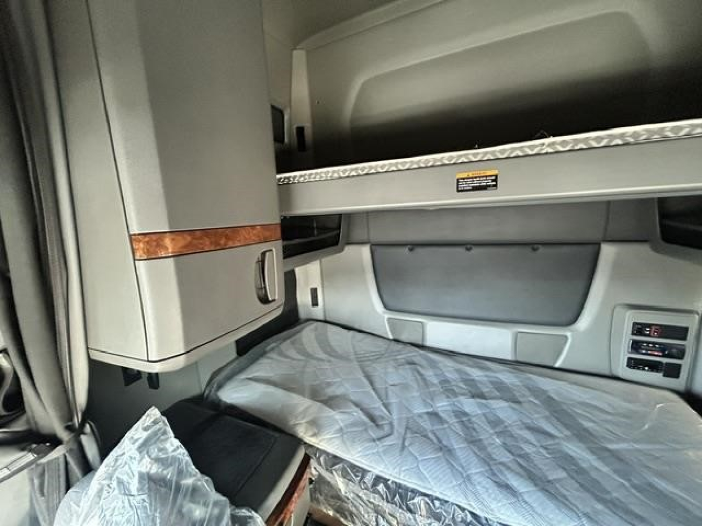Cabin interior of a used 2021 International LT truck sleeper showing bunk upper storage shelf and plastic-covered lower bunk.