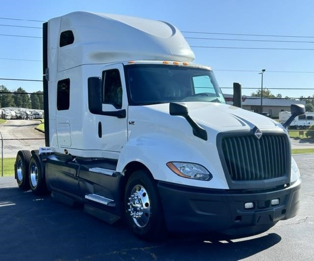 2021 International LT sleeper tractor in white showing front and side view with grille, headlights, and dual rear axles.