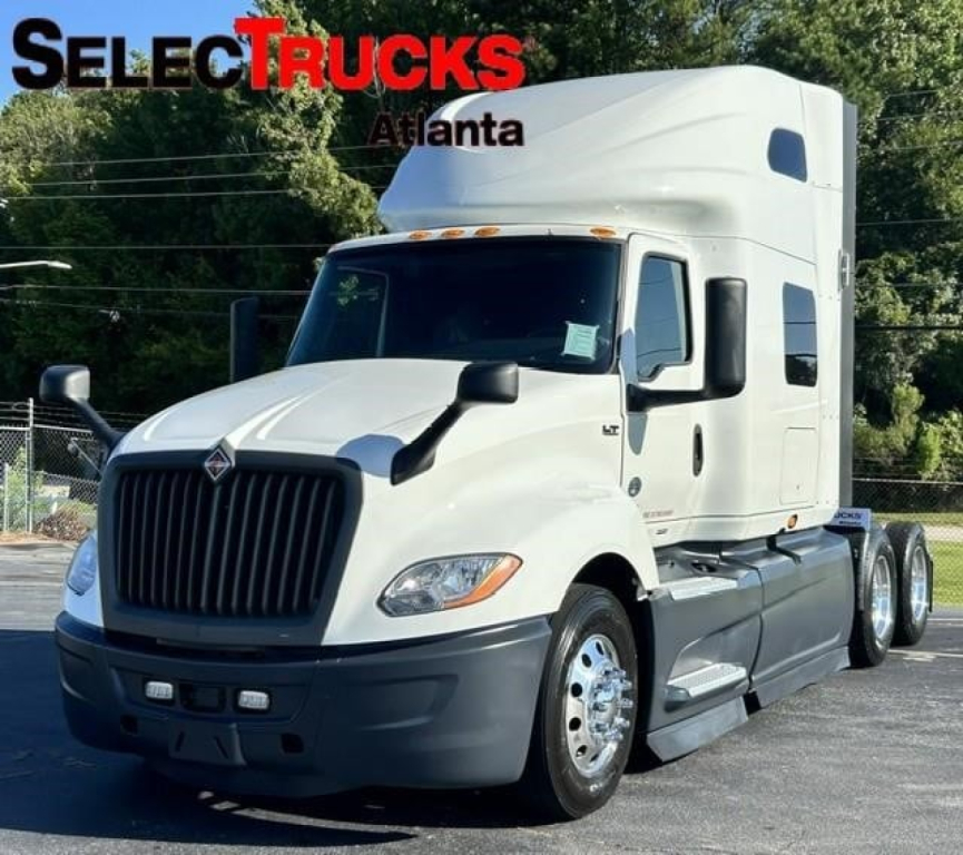 International LT truck cab and chassis in profile showing large grille and sleeper cab, white paint, SelectTrucks Atlanta watermark.