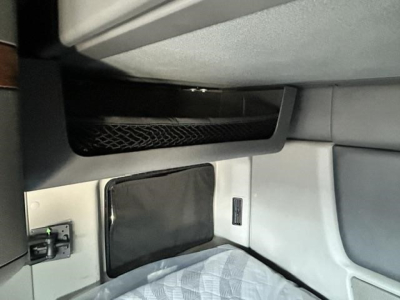 Truck cab interior panel with a storage pocket and a small door, showing a rectangular black panel and a side pocket; no legible alphanumeric text visible.
