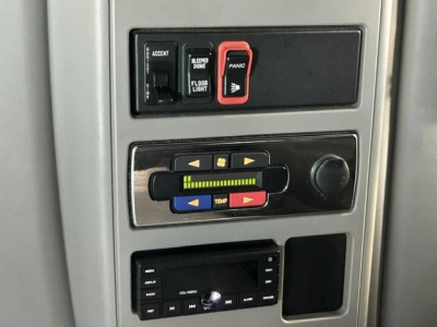 Truck interior switch panel showing Accent and Panik/panic? switches, floor light, sleeper done, and a control panel with colored arrow buttons and a knob. A stock radio or media unit is visible below.