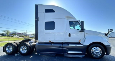 Truck side view showing 2021 International LT conventional sleeper with white cab and dual rear axles.