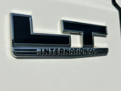 Close-up of a white truck with a chrome LT International emblem on the side, showing the International logo and word INTERNATIONAL.