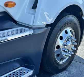 Truck front wheel and step showing chrome hubcap, treaded tire with 'R213' marking, and metal step; part of International LT conventional sleeper