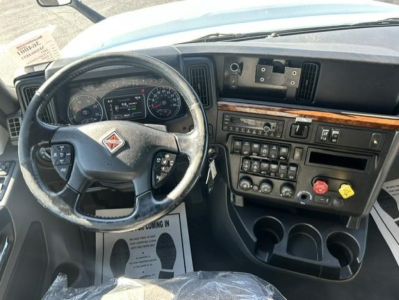 Interior cab of a 2021 International LT truck showing steering wheel with logo, dashboard gauges, center console with controls, and cup holders.