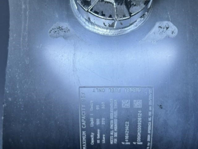 Label on truck showing maximum capacity and tire load data with a circular cap above. Text includes details like 'MAXIMUM CAPACITY' and various numeric specifications.