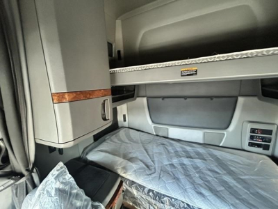 Cabin interior of a used 2021 International LT truck sleeper showing bunk upper storage shelf and plastic-covered lower bunk.