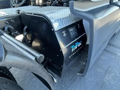 Truck engine bay area showing a black toolbox (?) with Tripac logo and HD+ emblem. Tanks and diamond plate cover visible.