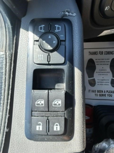 Truck interior showing window/lock controls panel with four lock/unlock buttons and a circular control pad.