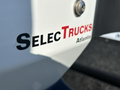 Tractor-trailer side showing SELEC TRUCKS Atlanta logo on white surface.