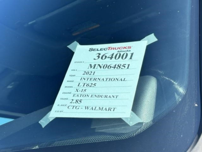 Label on windshield with truck details: Stock 364001, VIN MN064851, year 2021, make International, model LT625, engine X-15, transmission Eaton Fuller, ROE 2.85, CTG Walmart.
