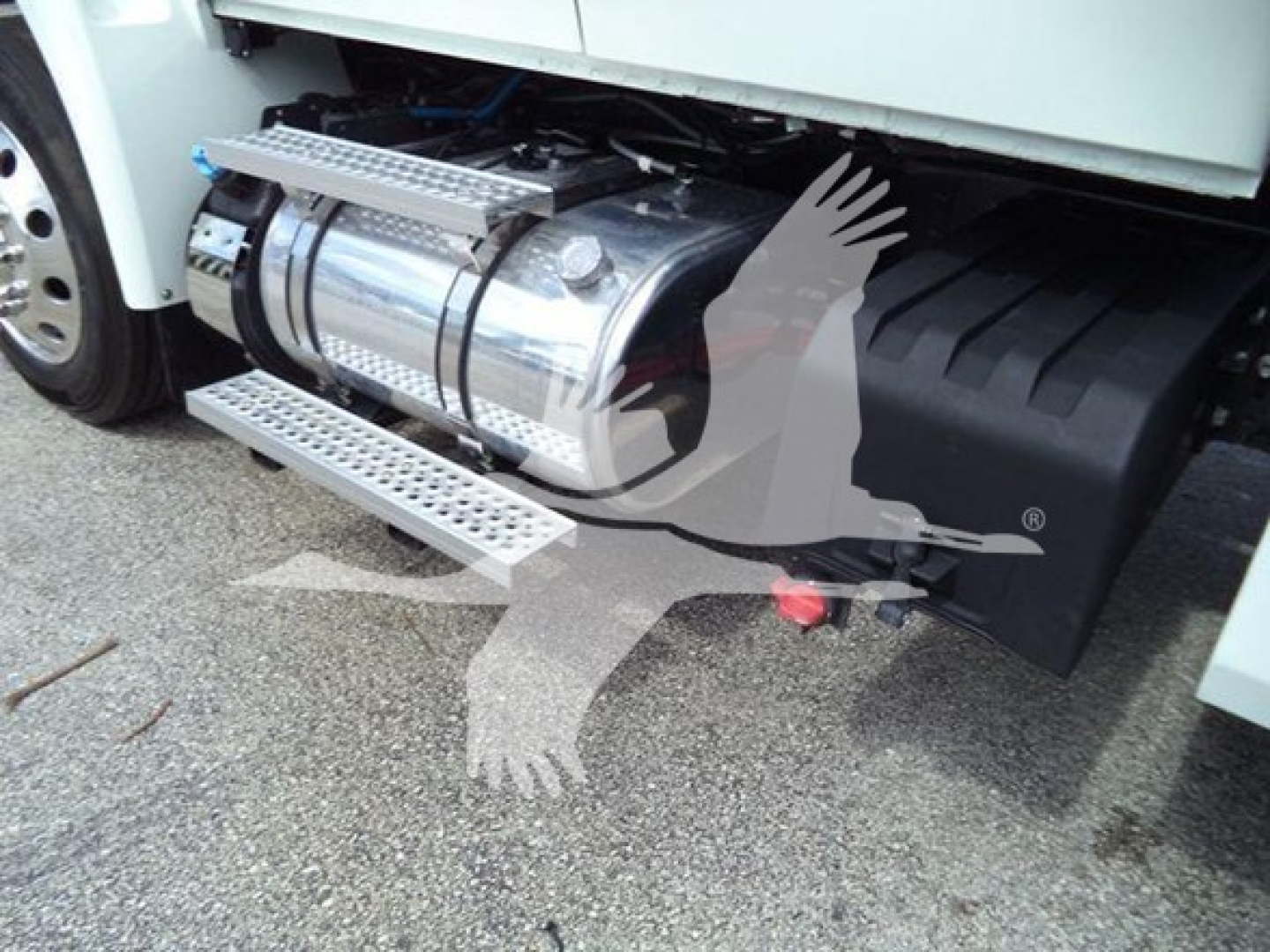 Truck fuel tank and side steps visible on a new International MV truck, chrome cylindrical fuel tank with steps and a black fender area.
