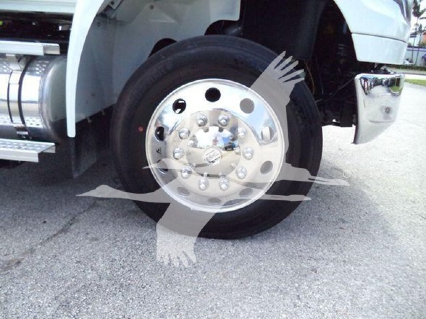 Wheel and front fender of a heavy-duty International truck showing polished chrome hubcap and tire, part of winch category listing.