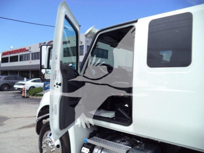 Truck cab interior showing open door and exposed engine bay with winch equipment aboard 2025 International MV truck.