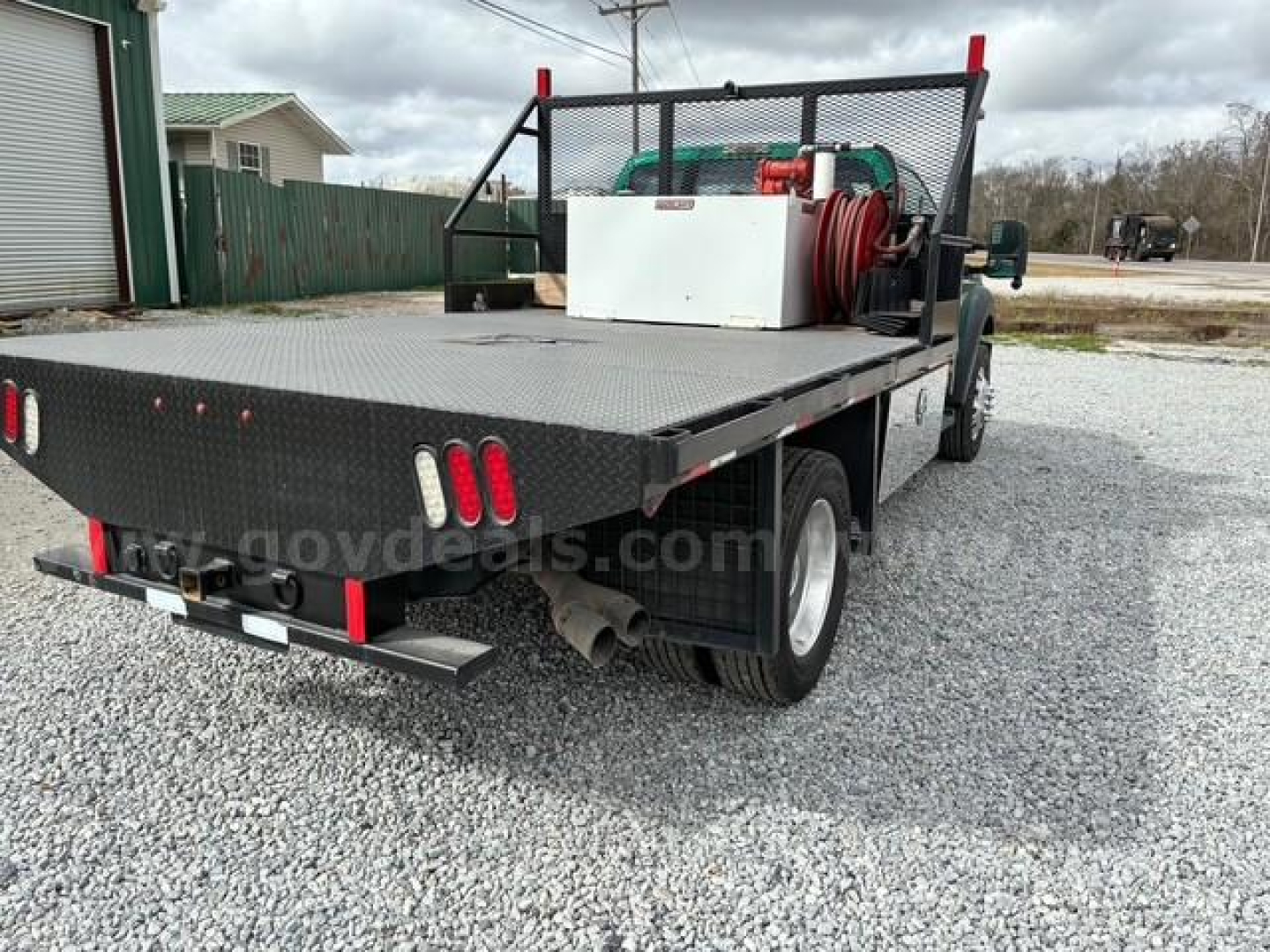Ford F-550 flatbed tow truck rear view showing flatbed with diamond plate, rear lights, and toolbox with hose reel.