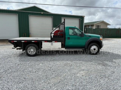 Ford F-550 flatbed truck side view showing green cab and flatbed with chrome tool/storage compartments.