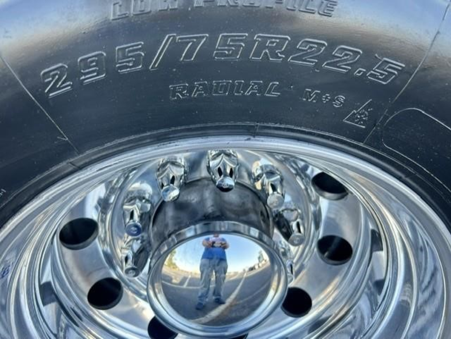 Tire sidewall showing 235/75R22.5 radial tire and polished steel wheel with center hub cap reflecting the photographer.