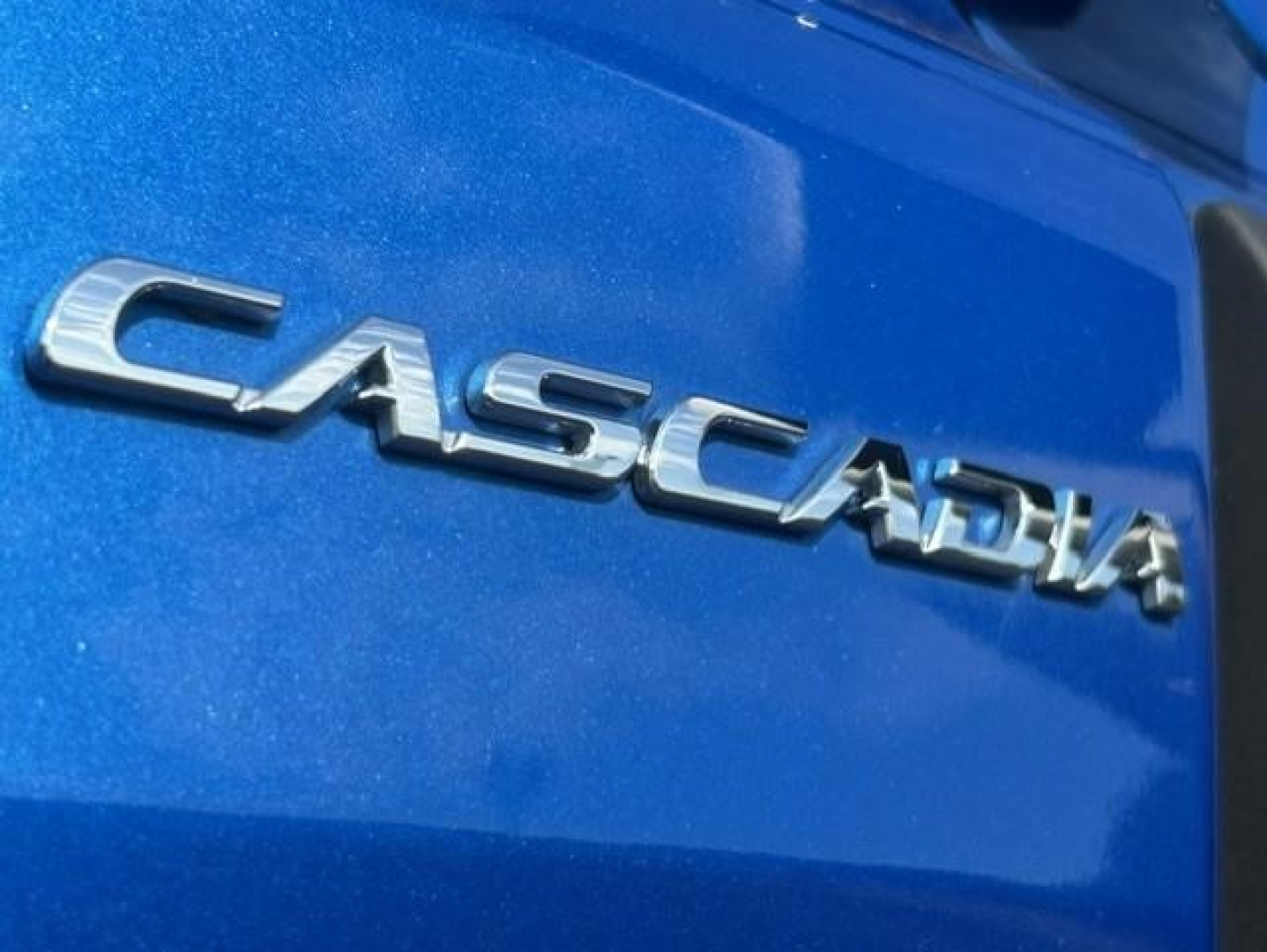 Freightliner Cascadia emblem on blue truck body showing CASCADIA chrome lettering.
