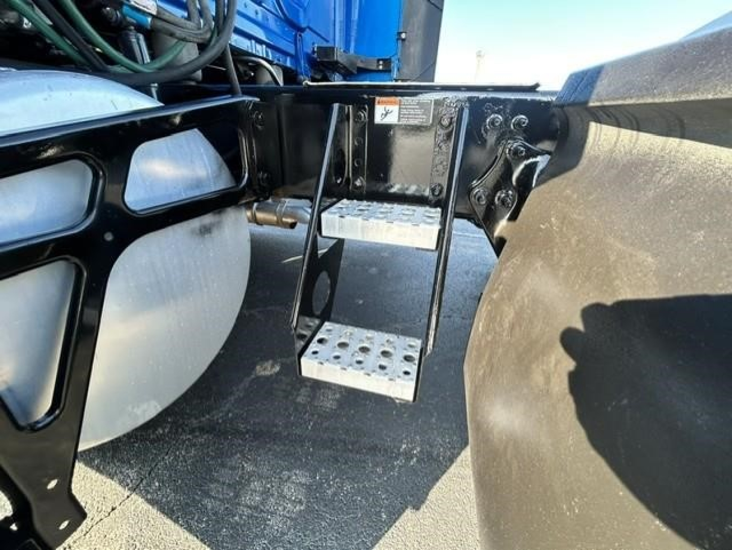 Truck steps and frame near fuel tanks showing metal perforated steps and mounting bracket.