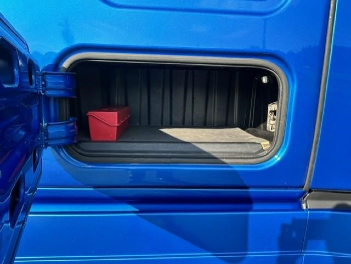 Freightliner Cascadia 126 truck cargo door open showing storage compartment with red tool box