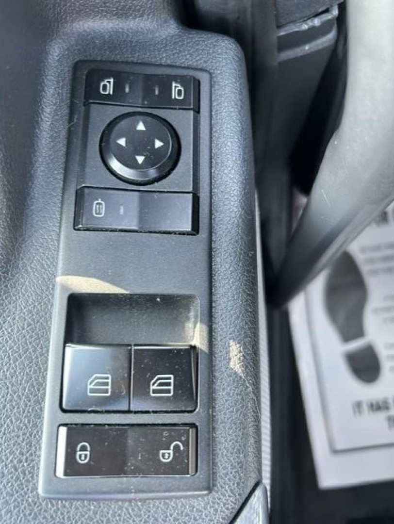 Panel of a Freightliner Cascadia door control switches and window controls showing lock/unlock and mirror adjustment buttons.