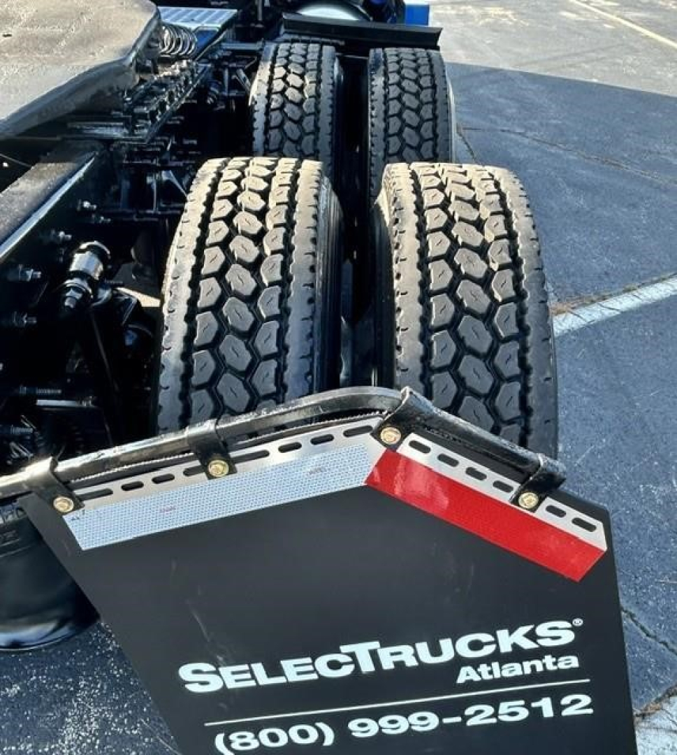 Dual rear axles of a Freightliner Cascadia truck with a reflective bumper plate displaying SelectTrucks Atlanta logo and phone number.