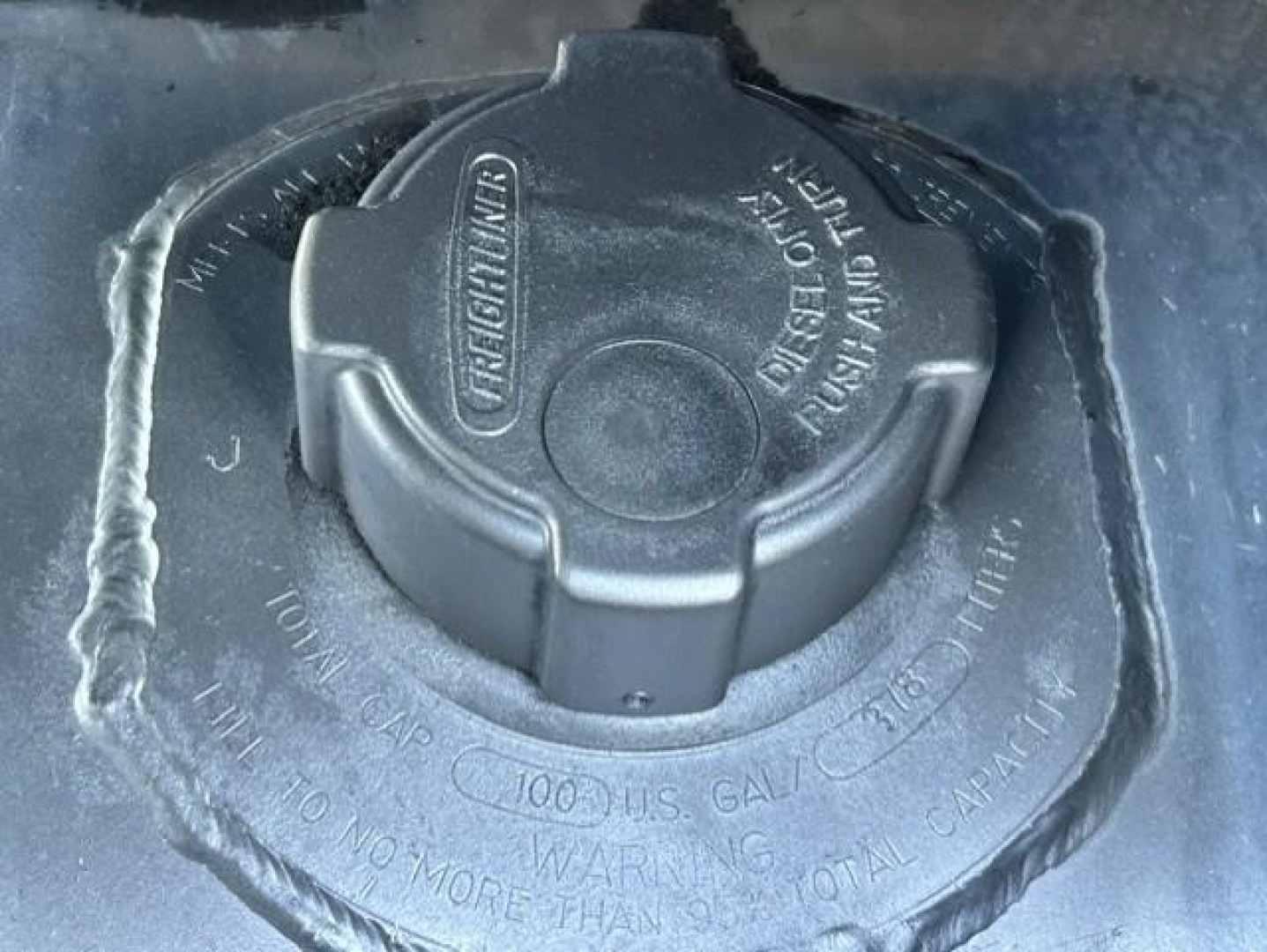 Vehicle fuel fill cap with stamped text around rim including 'GALLON' and 'DO NOT FILL ABOVE' may be part of Freightliner Cascadia image.