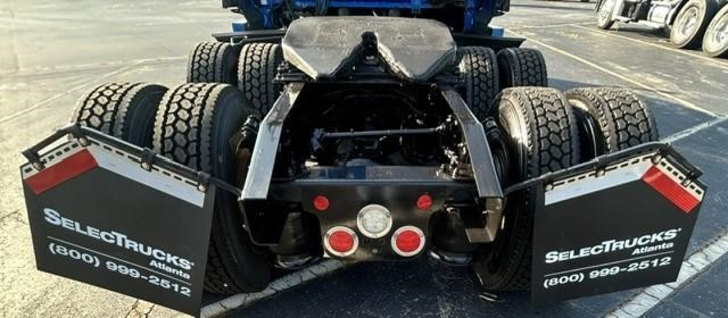 Rear view of a Freightliner tractor showing dual rear axles and mud flaps with SELECTTRUCKS branding.