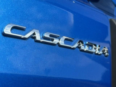 Freightliner Cascadia emblem on blue truck body showing CASCADIA chrome lettering.