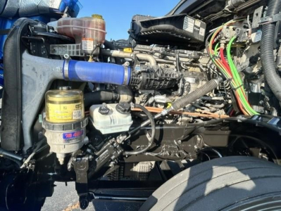 Freightliner Cascadia 126 engine bay showing blue silicone hose, yellow filters, and various wiring in service bay.