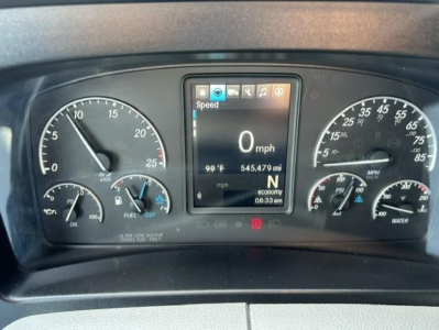 Vehicle dashboard of a Freightliner Cascadia showing digital speed readout at 0 mph, outside temp 99°F, odometer 545,479 mi, various gauges for fuel, oil, and water.