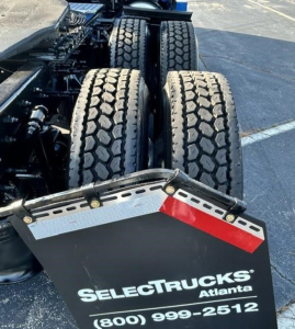 Dual rear axles of a Freightliner Cascadia truck with a reflective bumper plate displaying SelectTrucks Atlanta logo and phone number.
