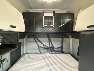 Freightliner Cascadia sleeper cab interior with bed, storage cabinet, and hanging net.
