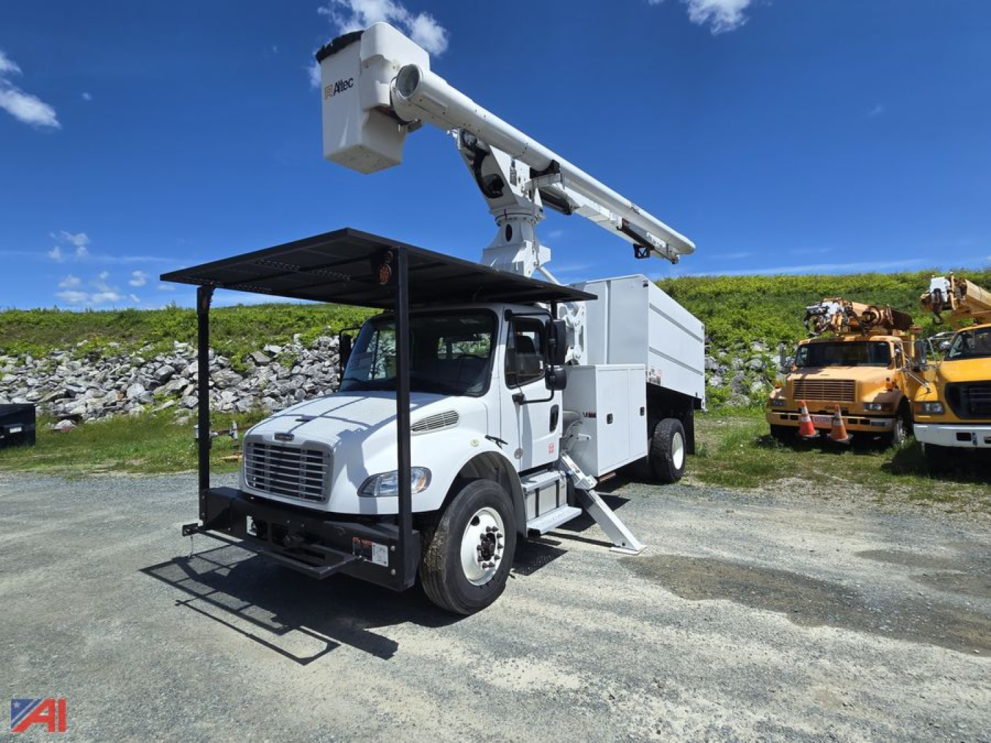 Bucket truck with Altec LRV-60E70 boom on Freightliner M2 106 utility chassis, white cab, elevated bucket, outriggers deployed, blue sky.