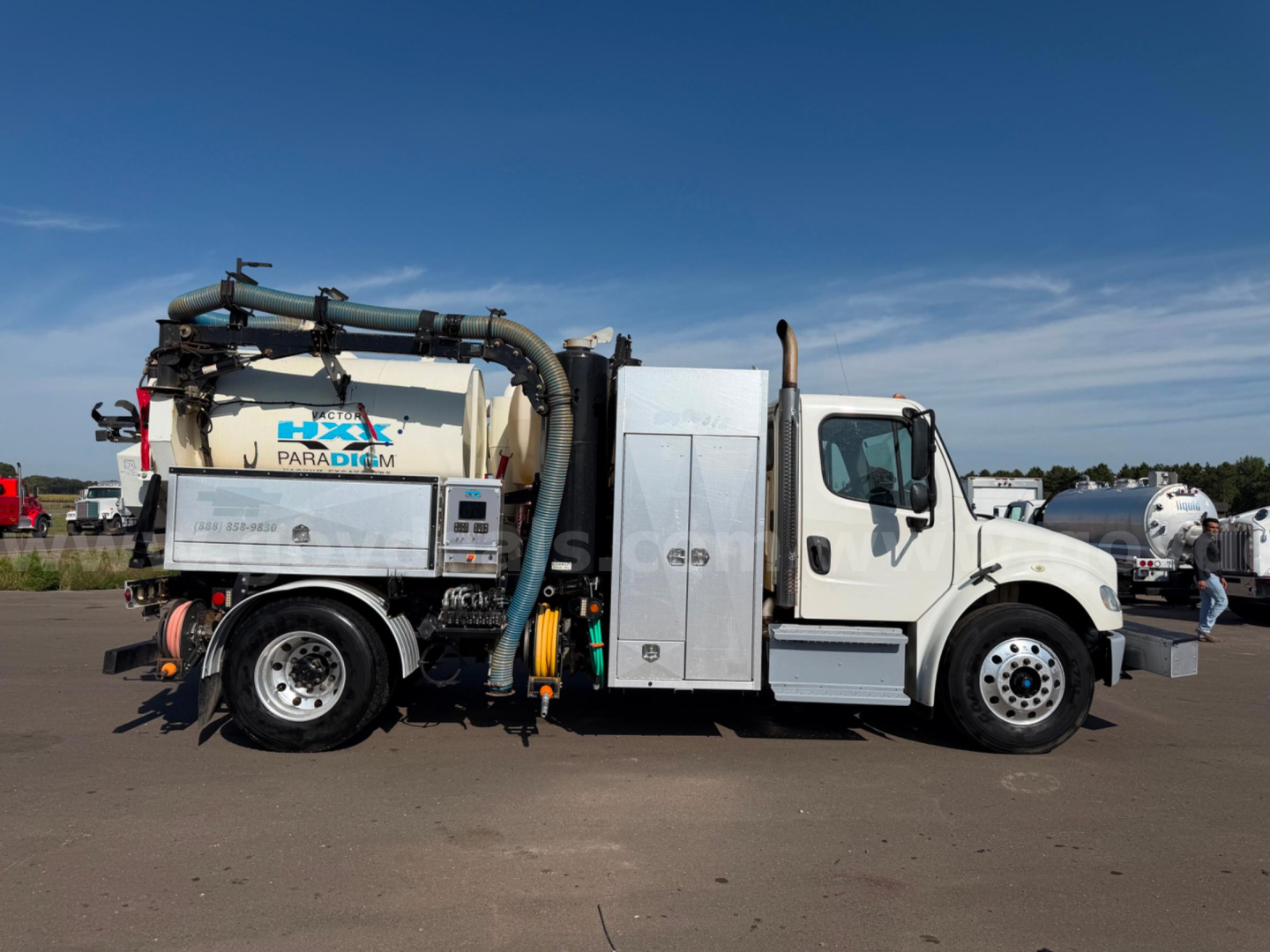 Freightliner vactor vacuum truck side view showing large white cab, cylindrical vacuum tank, and hoses with Paragon branding.