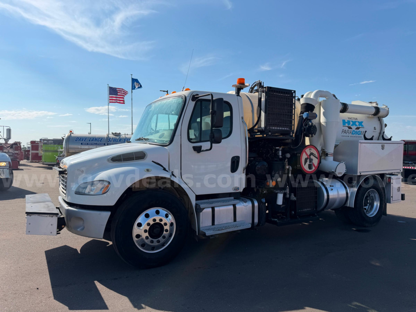 Freightliner Vactor vacuum truck side view showing large white tank with HXX equipment and hoses, front cab with dual rear wheels.