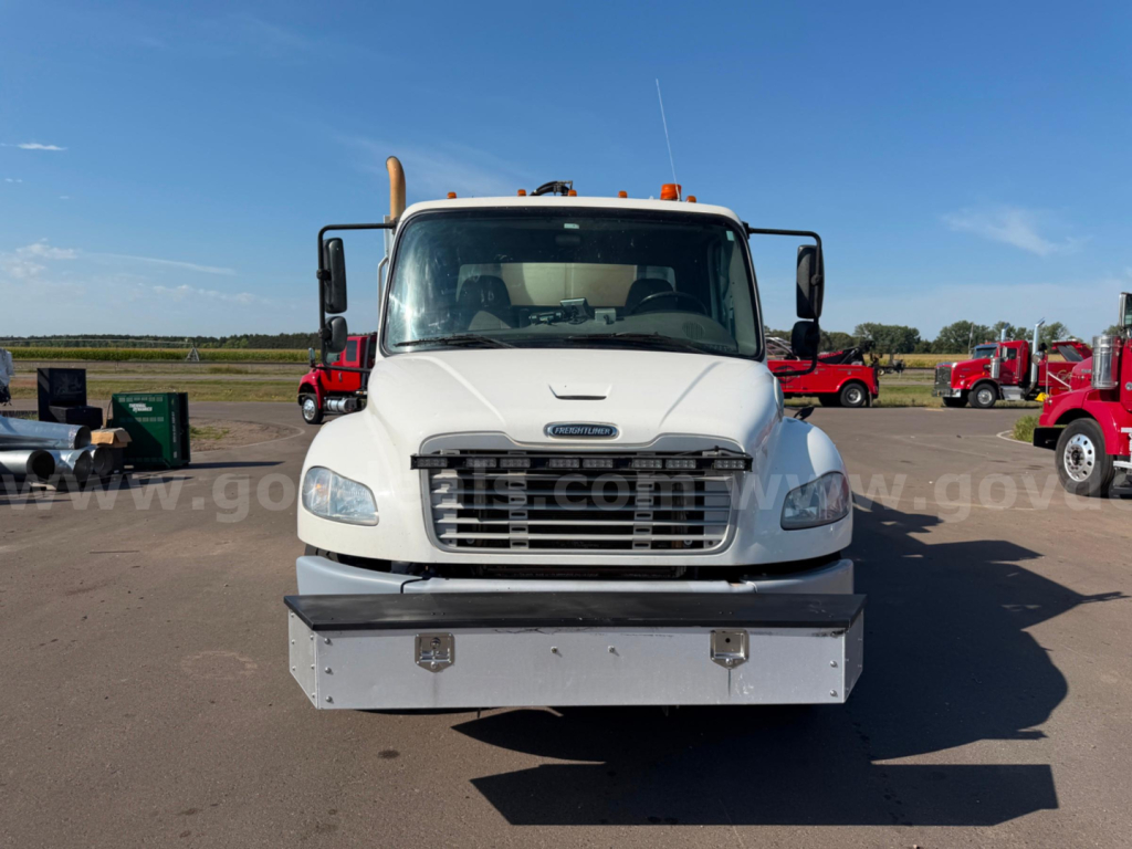 Front view of a white 2018 Freightliner Vactor truck showing large metal bumper and grille, with side mirrors and blue sky.