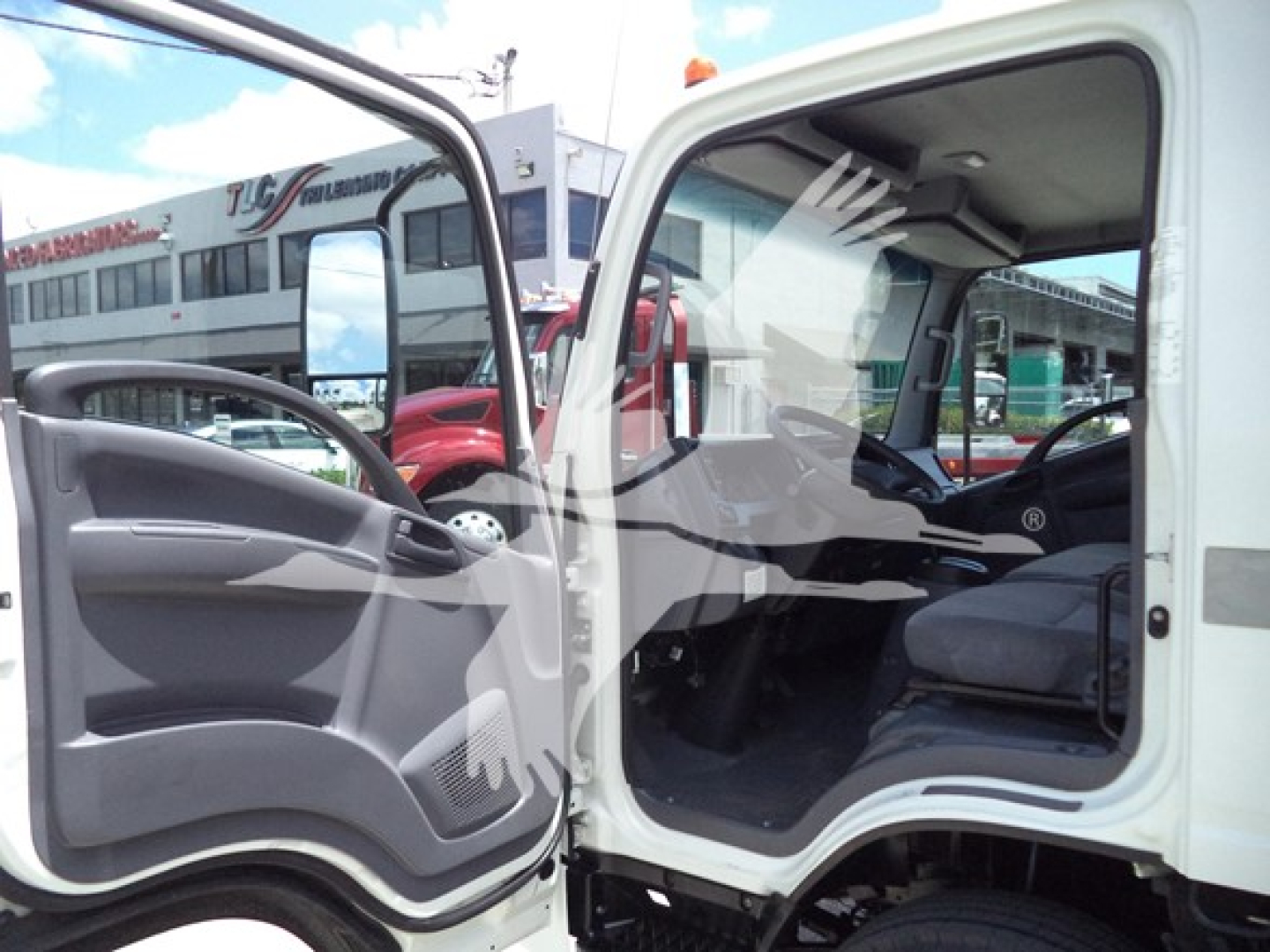 Isuzu NPR truck cab interior with open driver door showing seating and dashboard, exterior panel visible