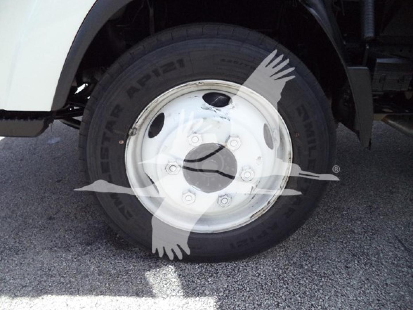 Wheel and tire close-up showing front wheel of Isuzu NPR with tire brand Arisun and white steel rim.