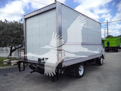 Truck side rear view showing Isuzu NPR box truck with metallic silver cargo box and white wheels.
