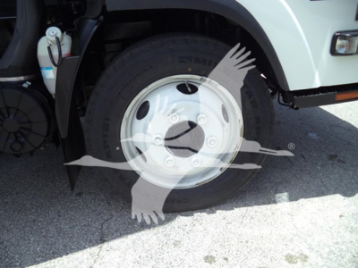 Isuzu NPR front wheel and fender showing steel wheel with hub and tire; part of truck undercarriage visible.
