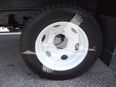 Isuzu NPR wheel area showing a white steel wheel with black tire and partial undercarriage. No legible labels or text visible on the wheel.