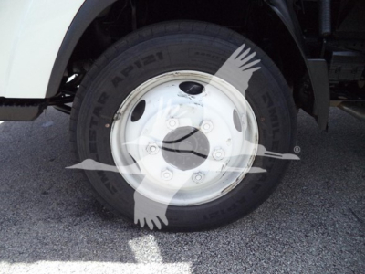 Wheel and tire close-up showing front wheel of Isuzu NPR with tire brand Arisun and white steel rim.