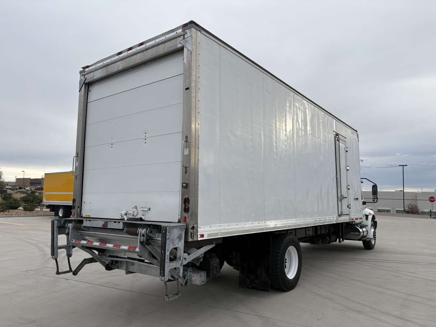 Truck rear and right side view of a 2020 International MV607 refrigerated box truck showing a large white cargo box with rear roll-up door and bumper.