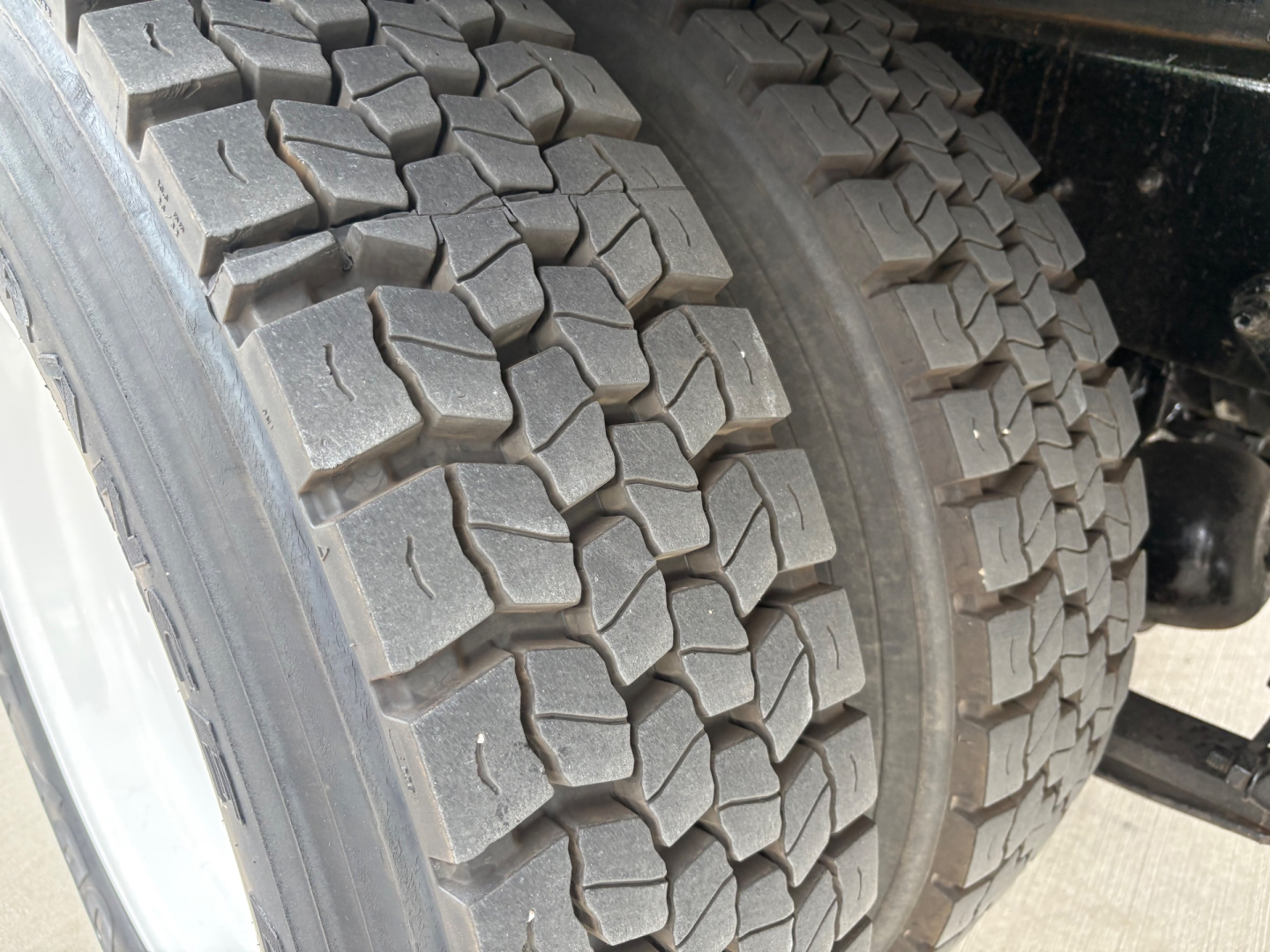 Truck rear dual tires with heavy tread on a refrigerated 2020 International MV607 showing dual tire ensemble and chassis components.