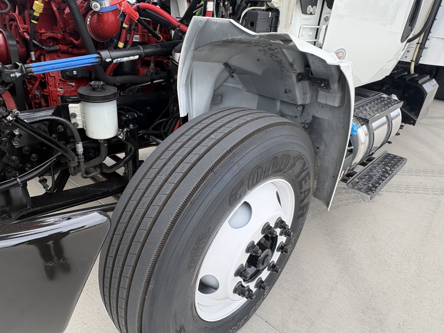 Truck front wheel well and engine bay of a 2020 International MV607 showing front tire, wheel, and exposed engine components