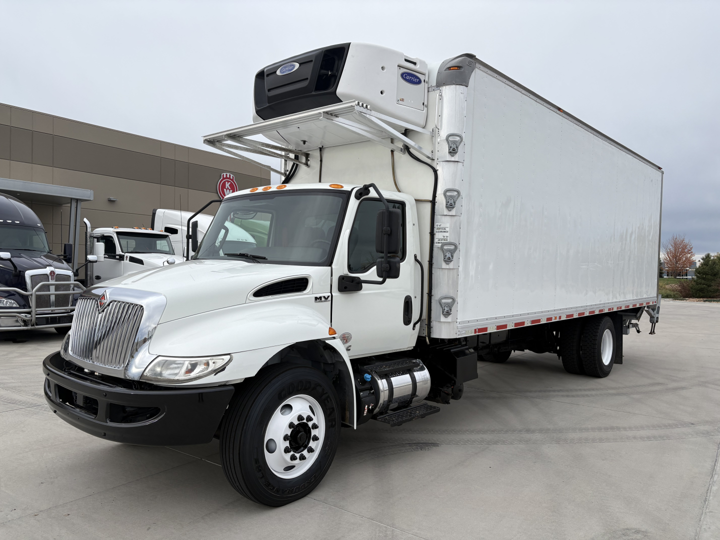 International MV607 refrigerated truck with a side-mounted refrigeration unit, white cab, and box trailer.